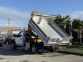 A 2008 Ford F-550 dump truck with its bed raised for unloading materials