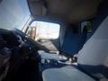 Interior view of a 2013 Mitsubishi Fuso FE 160 with two blue seats and a steering wheel visible in the foreground