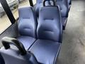 A row of blue upholstered bus seats with a contoured design set against a gray floor