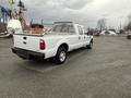 A white 2010 Ford F-250 SD truck with a utility bed and clean lines parked in an industrial area