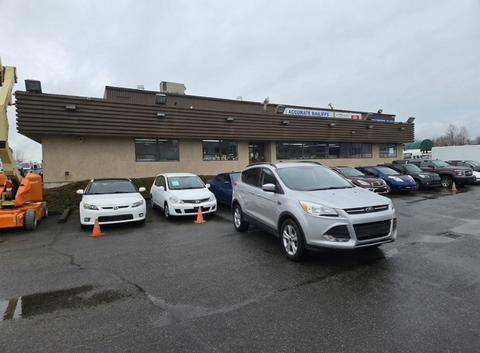A silver 2015 Ford Escape parked in front of a dealership among other cars