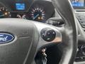 Close-up view of a steering wheel with a Ford logo and controls for audio and voice commands on a 2017 Ford Transit Connect