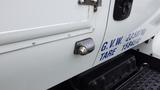 A close-up of a 2012 International 7400 truck door showing a fuel cap with a chrome insert and a black plastic housing alongside markings for weight and tare information