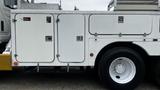 A white 2006 International 7500 truck with a storage compartment featuring metal doors and latches on its side