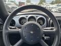 Steering wheel of a 2005 Chrysler PT Cruiser with various controls and gauges visible in the dashboard behind it