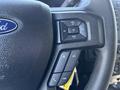 Close-up of a 2015 Ford F-150 steering wheel controls featuring audio volume buttons and a phone call button