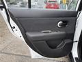 Interior door panel of a 2012 Nissan Versa featuring a black armrest a chrome door handle and a speaker grille