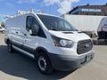 A 2016 Ford Transit van in white with a black lower panel and roof rails, featuring large side doors and a front grille with the Ford logo