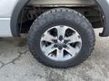 A close-up view of a 2014 Ford F-150 tire featuring a rugged Goodyear Wrangler tire on a silver alloy wheel