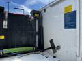 A 2009 Ford F-550 with an attached fuel tank and pump setup featuring green and black hoses and a warning label on a white surface