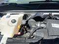 Engine compartment of a 2007 Chevrolet Express showing the coolant reservoir and air intake system with various hoses and components