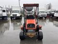A 2012 Kubota F3680 lawn mower with a prominent red body and a sturdy frame featuring a roll bar and large rear wheels positioned in a wet parking area