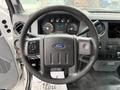 Close-up of the steering wheel of a 2012 Ford F-450 SD featuring controls for audio and phone along with the Ford logo in the center