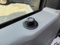 Close-up of a button on the door panel of a 2023 Ford E-450 with a textured surface and circular design