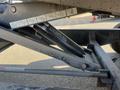 A close-up view of the hydraulic suspension of a 2024 Southland SL716-20K featuring the Champion logo on a shock absorber and detailed diagrams on a nearby panel