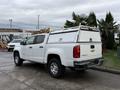 A white 2019 Chevrolet Colorado pickup truck with a canopy on the bed and ladder racks mounted on top