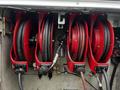 Interior compartment of a 2015 Ford F-550 showcasing four red hose reels with hoses coiled and ready for use