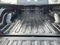 Interior view of the bed of a 2015 RAM 1500 with a textured black surface and molded side walls