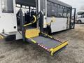 A 2017 Chevrolet Express with a wheelchair lift extended at the rear entrance featuring safety yellow handrails and red and white reflective markings on the lift