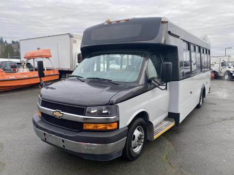 A white and black 2017 Chevrolet Express bus with a large windshield and side windows visible from the front angle