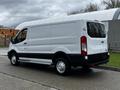 A white 2023 Ford Transit van with a high roof and a black lower section is parked with its side facing the viewer
