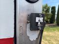 A close-up of a black control panel mounted on a metallic surface featuring an up and down arrow symbol for operation on a 2015 Freightliner M2 106 truck
