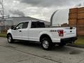 A white 2016 Ford F-150 with four-wheel drive features a spacious cab and a long bed positioned on a street