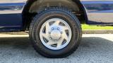 A close-up view of a silver wheel with five spokes mounted on a tire of a 2013 Ford Econoline