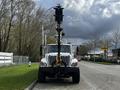 A 2008 International 7500 truck with a tall mounted light apparatus at the front, featuring a white body and yellow tow cable attached to the front bumper