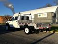 A white 2014 RAM 5500 with a flatbed and metal railing is parked, showcasing its sturdy design and large wheels