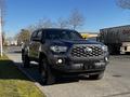 A 2021 Toyota Tacoma with a black exterior parked on a street featuring a distinctive front grille and rugged tires