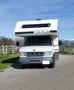 A 1998 Fleetwood Tioga Bunkbed recreational vehicle with a distinctive front design and large windshield parked on a gravel road