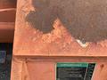 A weathered orange JLG E300AJP aerial lift with visible rust and faded identification numbers on its surface