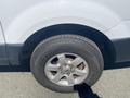 Close-up of a silver 2013 Ford Expedition's wheel with a steel rim and a rugged tire featuring visible tread patterns