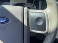 A close-up view of the dashboard of a 2013 Ford Expedition featuring the Ford emblem and part of the steering wheel with a textured surface