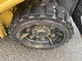 A close-up view of a large industrial tire with a rugged tread pattern and visible bolts on the wheel rim indicating heavy-duty use