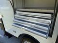 A 2023 Ford F-550 with open storage compartments showcasing multiple slide-out shelving units