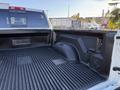 A 2023 RAM 3500 truck bed with a durable liner and storage compartment on the side