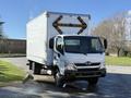 A 2014 Hino 195 box truck with a white body and prominent rear lights is parked in a lot facing forward