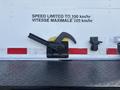 A black lever with a curved handle mounted on a white truck panel featuring speed limit signs in English and French