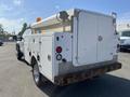 A 2015 Ford F-450 SD service truck with a white utility body featuring compartments and a light bar on the roof