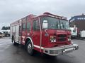 A red 2006 E-One fire truck with a front grill featuring lights and a siren marked with "FIRE DEPT" on the side and an open compartment for equipment