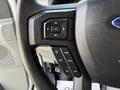 Close-up of the steering wheel controls of a 2023 Ford E-450 featuring buttons for setting cruise control and adjusting settings