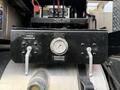 A black control panel with two silver levers labeled ON and OFF and a pressure gauge indicating reservoir pressure