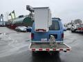 A blue 2006 Ford Econoline van with a mounted overhead work platform on the back