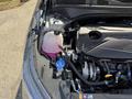 A 2024 Kia Forte5 engine compartment featuring a turbocharged engine with visible components such as a coolant reservoir and various hoses