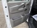 The image shows the inside door panel of a 2015 GMC Savana featuring a handle multiple storage compartments and a textured surface