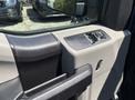 Close-up view of the interior door panel of a 2015 Ford F-150 featuring window controls and a textured armrest design