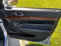 The interior door panel of a 2013 Lincoln MKT featuring wood grain trim power window controls and a leather finish