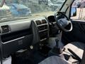 Interior view of a 2009 Suzuki Carry featuring a dashboard with controls gear shift and seating with a cloth pattern